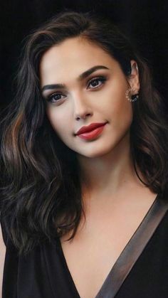 a woman with long dark hair and red lipstick wearing a black dress is posing for the camera