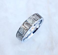 a silver ring with an intricate design on the outside and inside, sitting on a white surface