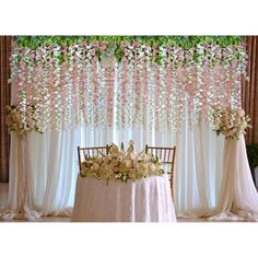 the table is set up with flowers and greenery hanging from the wall behind it