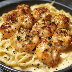 pasta with scallops and parmesan cheese in a black bowl on a table