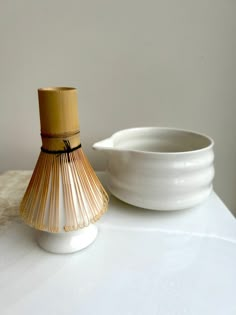 a white bowl sitting next to a bamboo vase