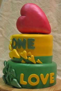 a three tiered cake with an apple on top and the words one love painted on it