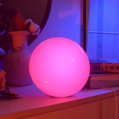 an illuminated ball sitting on top of a table next to a vase with flowers in it