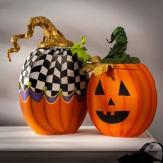 two carved pumpkins sitting side by side on a shelf with decorations in the shape of jack - o'- lanterns