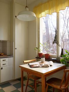 a kitchen with a table and two chairs in front of a window that looks out onto the woods