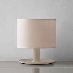 a white lamp sitting on top of a table next to a gray wall and floor