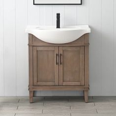 a white sink sitting under a mirror on top of a wooden cabinet next to a wall