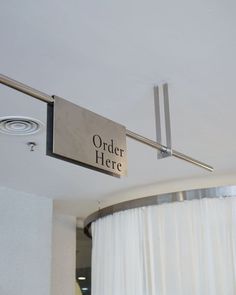 there is a sign that says order here hanging from the ceiling in front of curtains