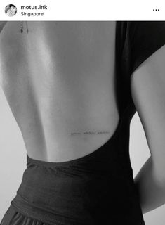 the back of a woman's neck with a small tattoo on her left side