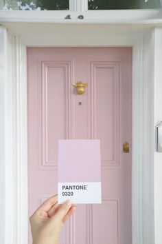 a person holding up a pink door with the name pantone on it