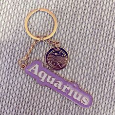 a purple and gold keychain with the word aquarius on it's side