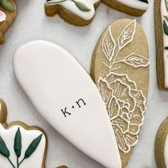 cookies decorated with flowers and leaves are arranged in the shape of surfboards that read k n