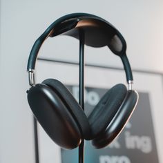 two black headphones are hanging on a stand