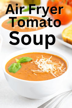 two white bowls filled with tomato soup and topped with parmesan cheese, basil leaves