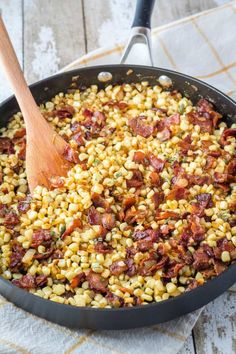 corn and bacon in a skillet with a wooden spoon