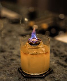 a close up of a glass on a table with a lit candle in the middle