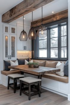 a kitchen table with benches and lights hanging from it's ceiling in front of a window