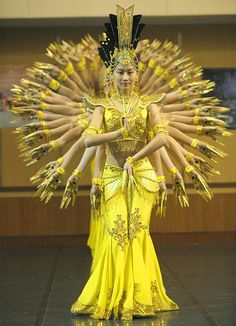 a woman in a yellow dress with lots of hands on her hips and arms outstretched