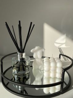 a glass table topped with candles next to a vase filled with liquid and reeds