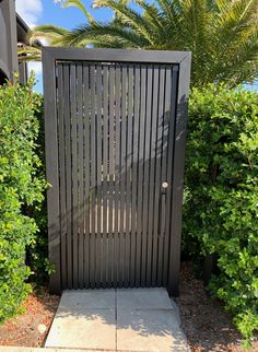 a black metal gate in front of some bushes