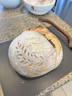 a loaf of bread sitting on top of a counter next to a knife and bowl