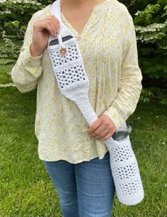 a woman is holding a crocheted device in her right hand and smiling at the camera