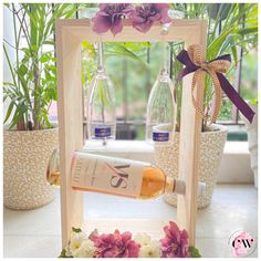 a wine bottle is being poured into a glass in front of some flowers and potted plants