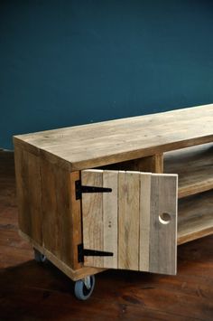 a wooden entertainment center on wheels in front of a blue wall and wood flooring