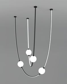 three black and white lights hanging from the ceiling in an empty room with gray walls