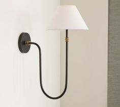 a lamp that is on the wall next to a white light fixture with a black arm