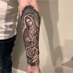 a person with a tattoo on their arm holding a rose and an image of the virgin mary