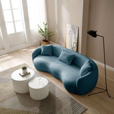 a blue couch sitting on top of a hard wood floor next to a white table