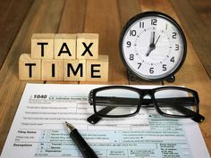 glasses, pen and eyeglasses sitting on top of tax form next to an alarm clock