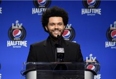 a man standing at a podium in front of a blue wall with the pepsi logo on it