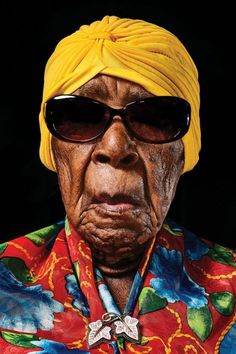 an old woman wearing sunglasses and a yellow turban