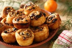 a plate full of cinnamon rolls on a table next to an orange and pine tree