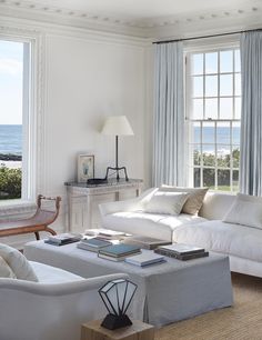 a living room filled with white furniture and windows