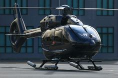 a helicopter that is sitting on the ground in front of a building with its landing gear down