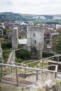 the stairs lead up to an old castle like structure in town, with trees and buildings around it