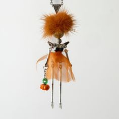 an orange necklace with feathers and beads hanging from it's side on a chain