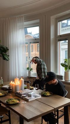 two people sitting at a table with food and candles