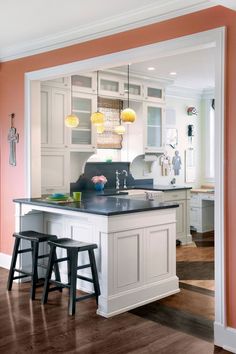 an open kitchen with two stools in front of the island