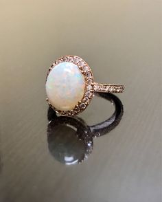 an opal and diamond ring sits on a table