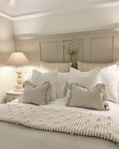 a white bed with pillows and blankets on it in a bedroom next to two lamps