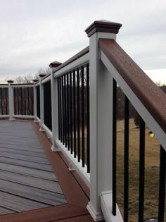 a wooden deck with black railing and white posts