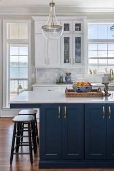 a kitchen with blue cabinets and an island in front of the window that has a basket of fruit on it