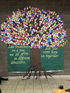 a tree made out of handprints on a green wall with words written underneath it