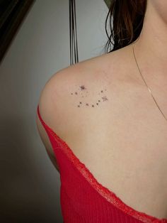 a woman wearing a red top with stars on her chest and arm tattooing it's left shoulder