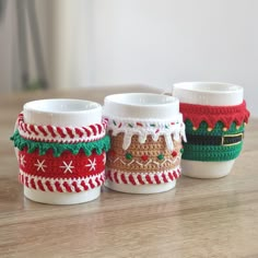 three coffee cups with knitted christmas sweaters on them