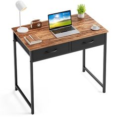 a laptop computer sitting on top of a wooden desk next to a lamp and potted plant